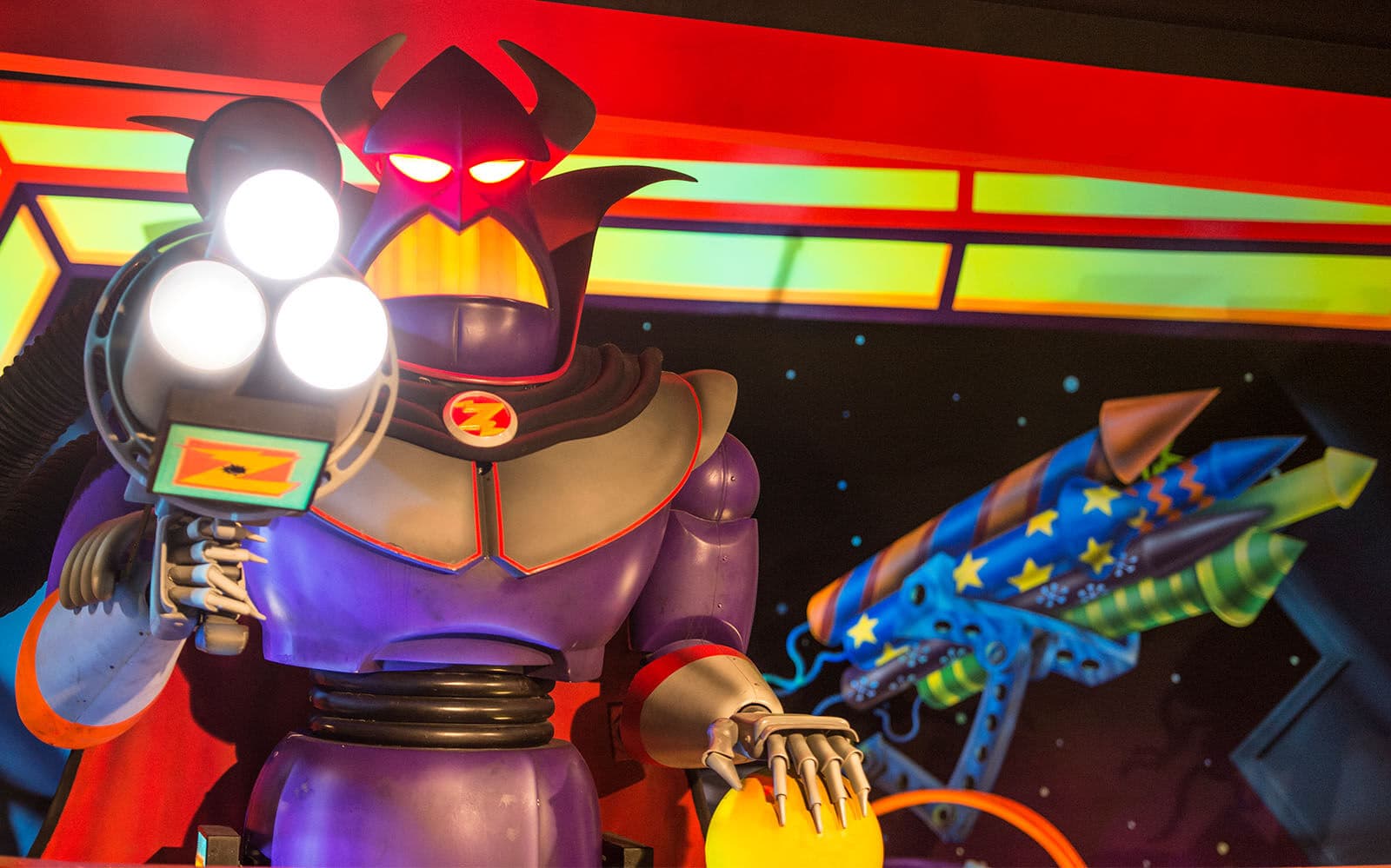 Imperatore Zurg con occhi rossi punta un'arma luminosa davanti a razzi spaziali colorati.