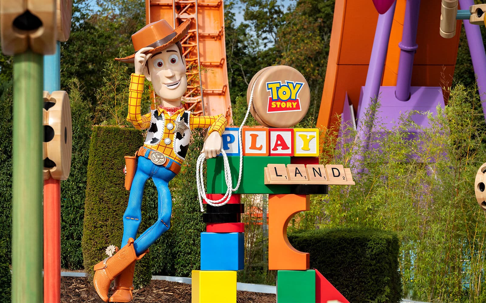 Statua di Woody appoggiata a cubi colorati che formano la scritta Toy Story Playland.