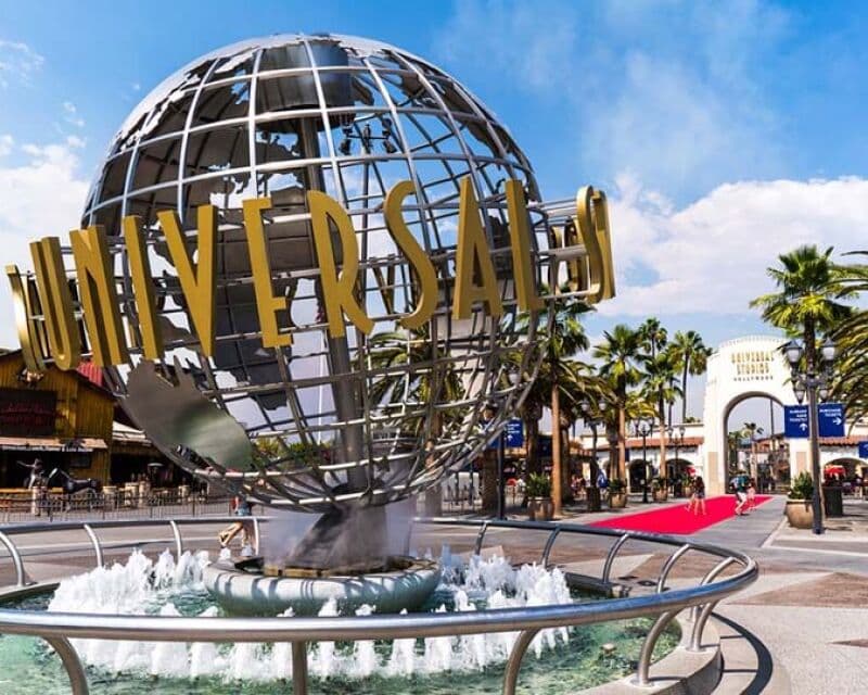Il celebre globo della Universal Studios Hollywood con fontana e palme sotto il sole.