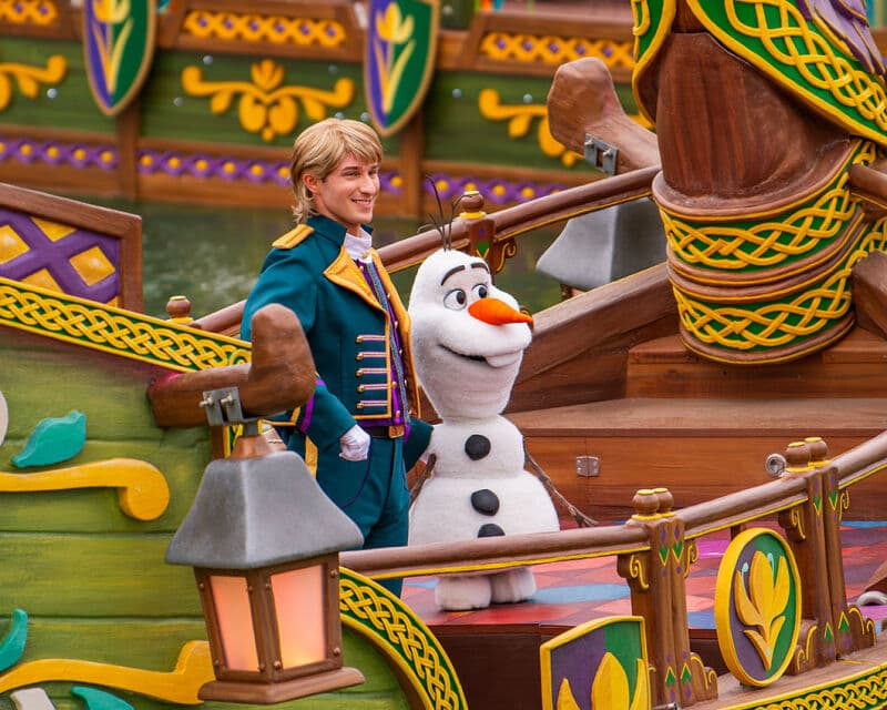 Kristoff e Olaf di Frozen sorridono su un carro allegorico in legno riccamente decorato.